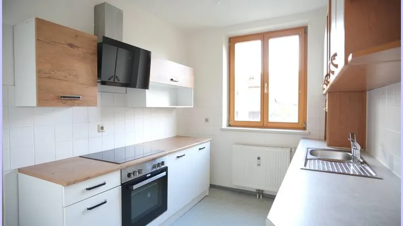 Helle Küche mit modernen Holz- und weißen Schränken, Induktionskochfeld und Backofen.