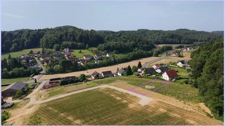 Luftaufnahme eines ländlichen Gebiets mit Häusern, Feldern und Wäldern, wobei ein Grundstück hervorgehoben ist.