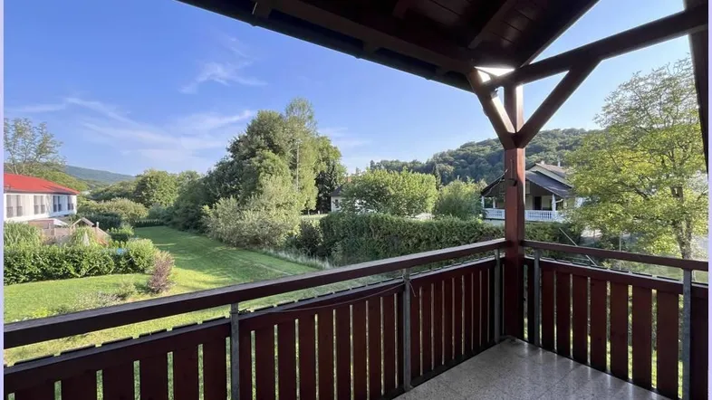 Geräumiger Balkon mit Holzelementen und weitem Blick ins Grüne und auf die umliegende Landschaft.