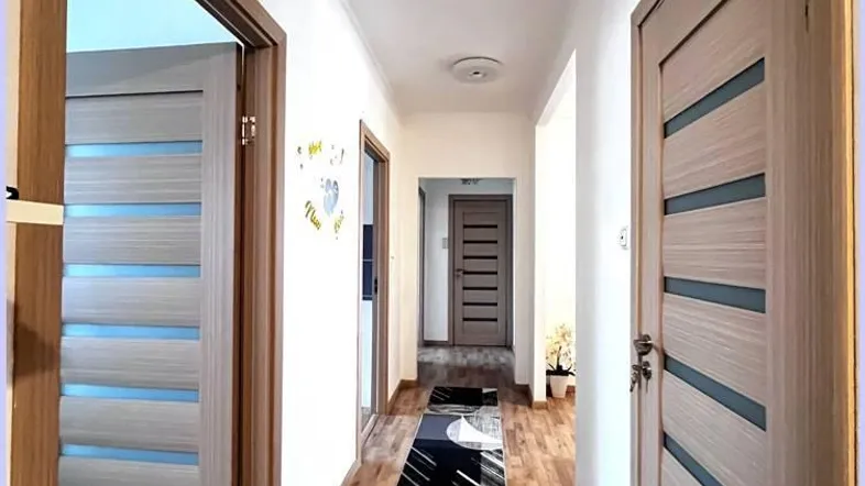 Langer Flur mit Holzboden und modernen Türen, der die verschiedenen Wohnbereiche verbindet.