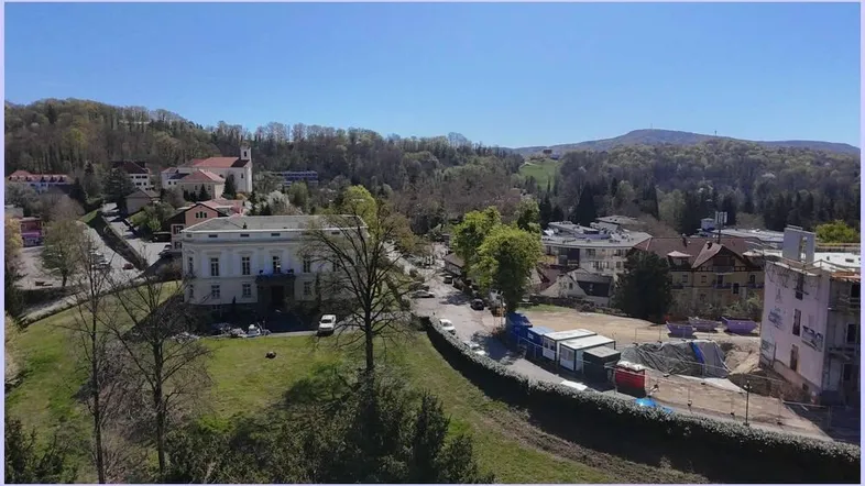 Panoramablick auf eine charmante Stadt mit historischen Gebäuden, grünen Hügeln und einem Kirchturm.