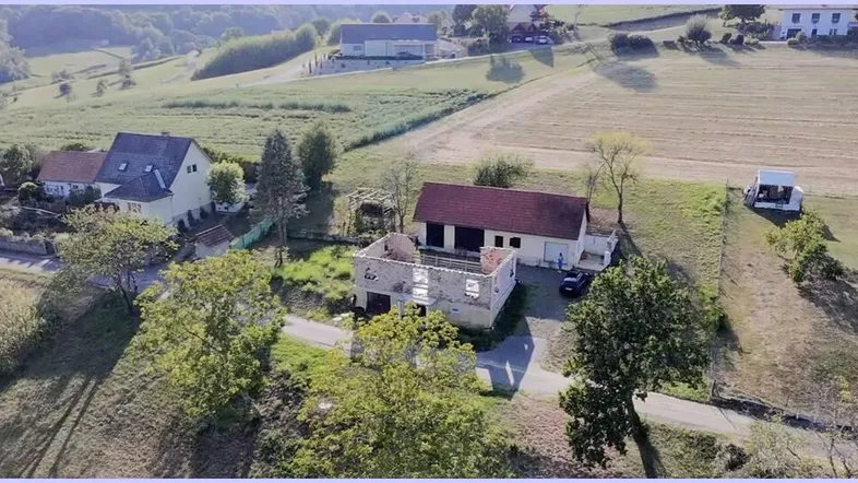 Luftaufnahme eines Grundstücks mit einem teilweise abgerissenen Gebäude und einem weiteren Haus in ländlicher Umgebung.