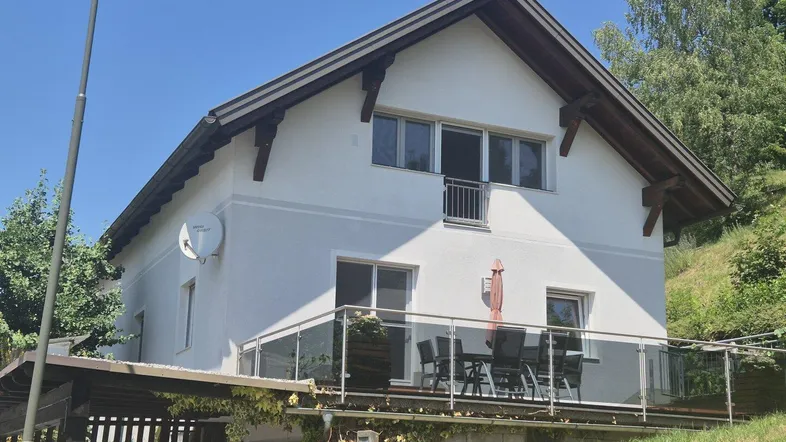 Modernes Haus mit großer Terrasse, Essbereich im Freien und angrenzendem Carport.