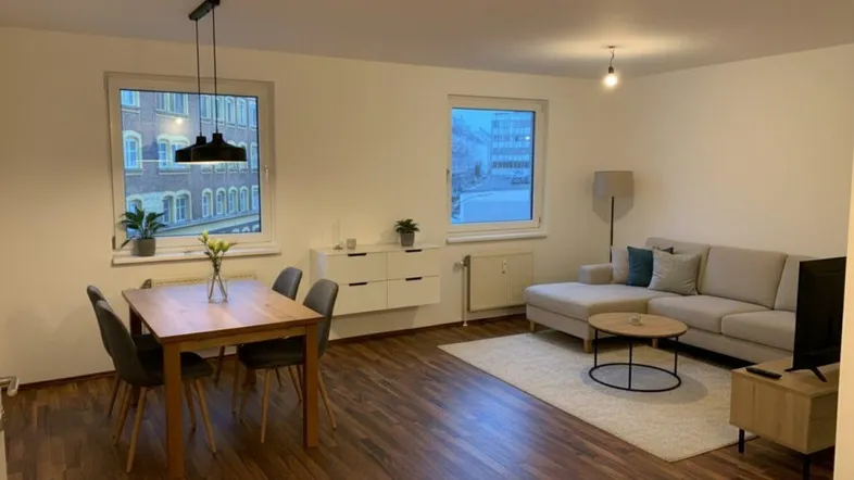 Heller Wohn- und Essbereich mit modernem Laminatboden und Blick auf die Stadt.