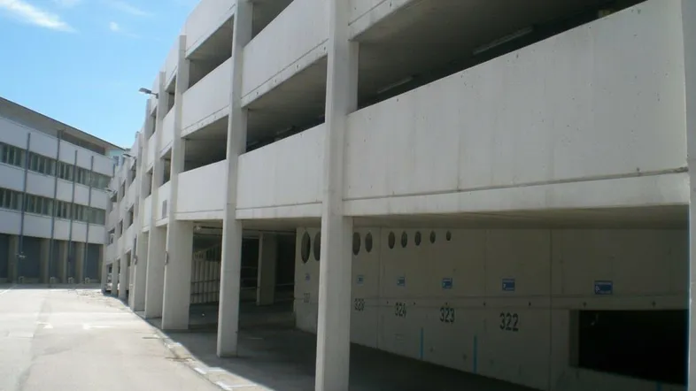 Ansicht eines modernen, mehrstöckigen Parkhauses aus Beton mit nummerierten Parkplätzen und einer geraden Linienführung.