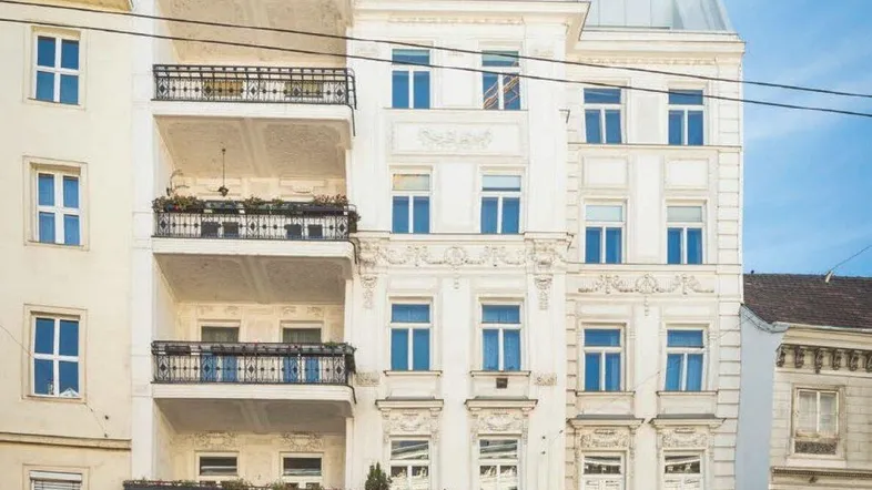 Historische Fassade eines eleganten Altbaus mit mehreren Balkonen und kunstvollen Verzierungen.