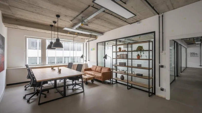 Modernes Büro mit Besprechungsbereich, Ledersofa und freiliegenden Deckeninstallationen.