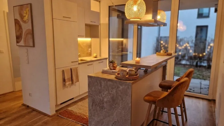 Moderne Küche mit Kochinsel, Barhockern und Zugang zu einem kleinen Außenbereich.