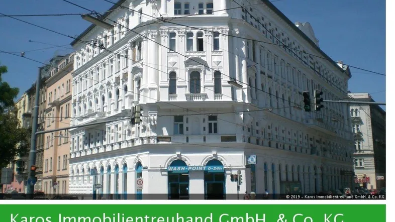 Historisches Gebäude mit weißer, reich verzierter Fassade an einer Straßenecke in der Stadt.