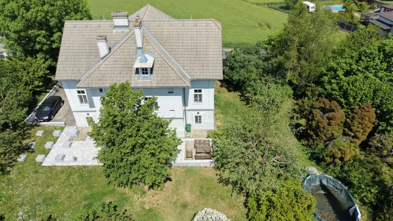 Luftaufnahme des Hauses mit großem Garten, gepflasterten Bereichen und ländlicher Umgebung.
