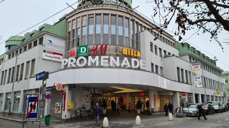 Gesamtansicht eines modernen Einkaufszentrums mit mehreren Geschäften und einer markanten Kuppel.
