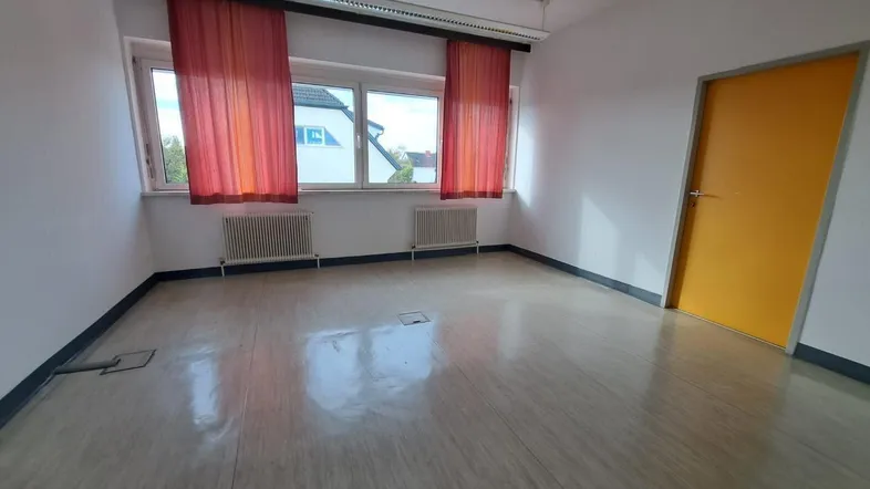 Leerer Raum mit großen Fenstern, orangefarbenen Vorhängen und einem gelben Türblatt.
