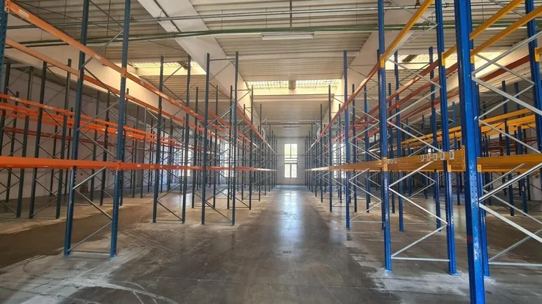 Große Lagerhalle mit hohen Regalsystemen und Betonboden, ideal für industrielle Nutzung.