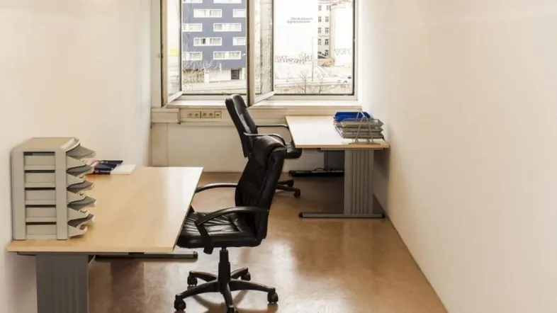 Helles Büro mit zwei Arbeitsplätzen, großen Fenstern und Blick auf die Stadt.