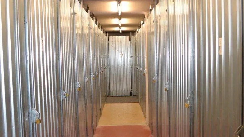 Langer Gang mit vielen individuellen Lagerabteilen und Deckenbeleuchtung in einem Kellerbereich.
