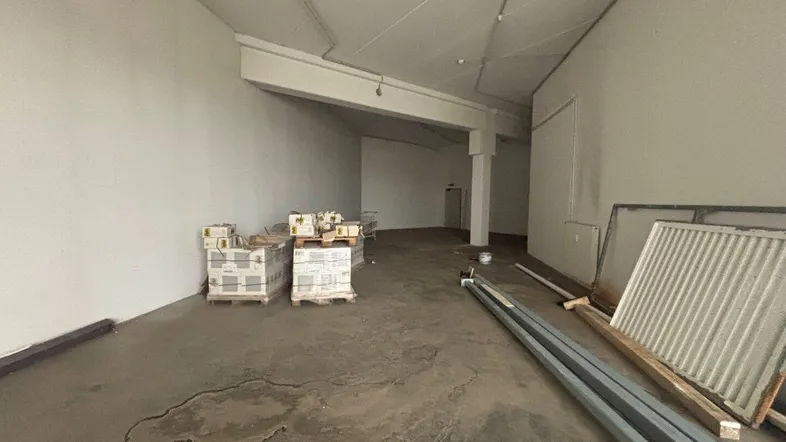Geräumiger, leerstehender Gewerberaum mit Betonboden und sichtbaren Deckeninstallationen, bereit für den Ausbau.