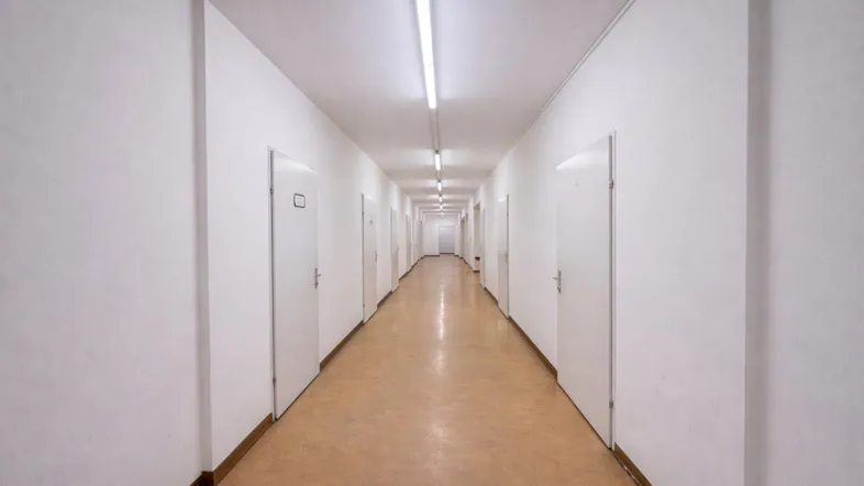 Langer, heller Flur mit zahlreichen Türen und funktionaler Beleuchtung, der zu verschiedenen Räumen führt.