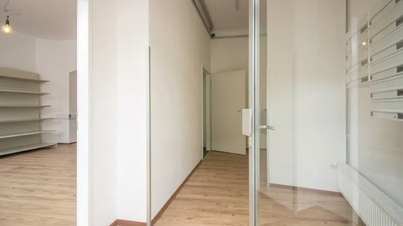 Heller Innenraum mit Laminatboden, weißen Wänden und einer Glastür, ideal für ein Geschäft oder Büro.
