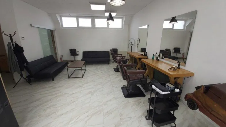 Geräumiger Gewerberaum, eingerichtet als Friseursalon, mit hellen Fliesen und großen Spiegeln.