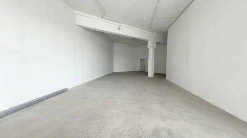 Geräumige, leere Gewerbefläche mit hohen Decken und einem robusten Betonboden, ideal für verschiedene Nutzungen.