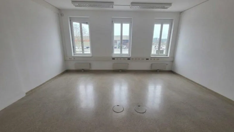Heller, leerer Raum mit drei Fenstern und strapazierfähigem Bodenbelag, ideal als Bürofläche nutzbar.