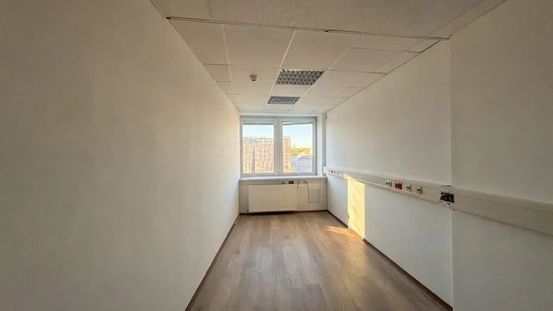 Langer, schmaler Raum mit Laminatboden, Fenster und abgehängter Decke, ideal als Büro oder Flur.
