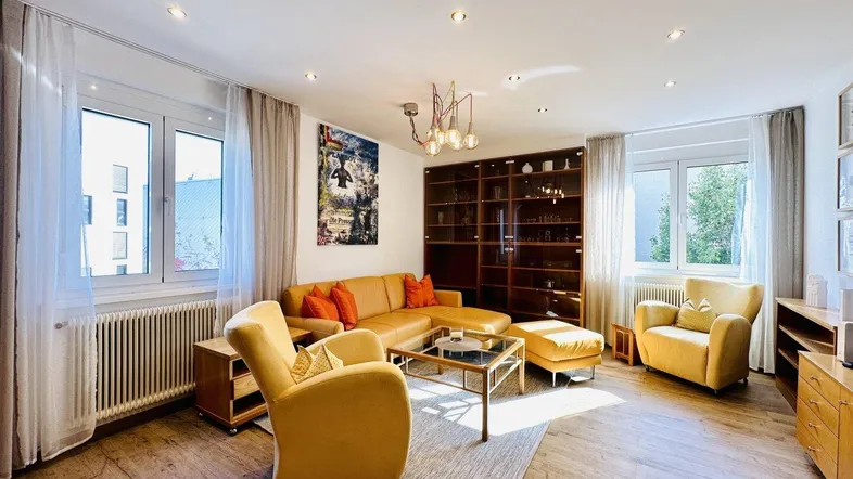 Helles Wohnzimmer mit gelben Möbeln, Holzboden und integrierten Regalen.