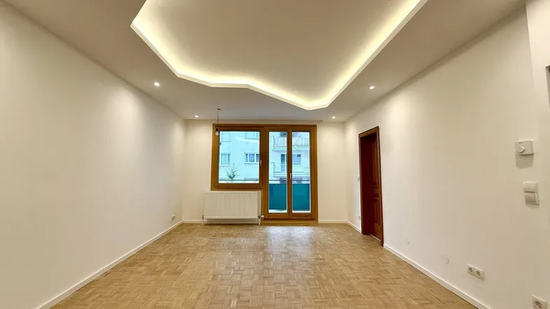 Helles Wohnzimmer mit Parkettboden, modernen Deckenleuchten und Zugang zum Balkon.