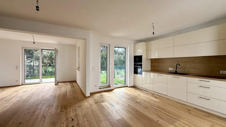 Moderne offene Küche und Wohnbereich mit Holzboden und Zugang zum Garten.