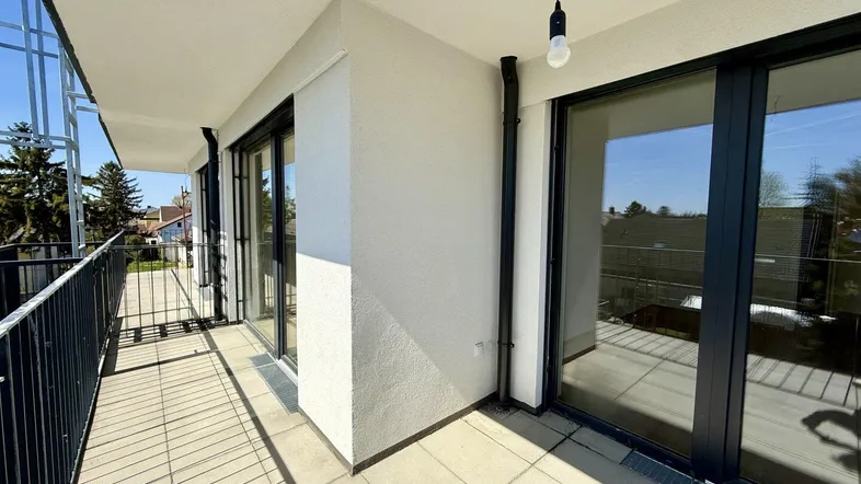 Geräumiger Balkon mit Fliesenboden und Metallgeländer, bietet viel Platz im Freien.