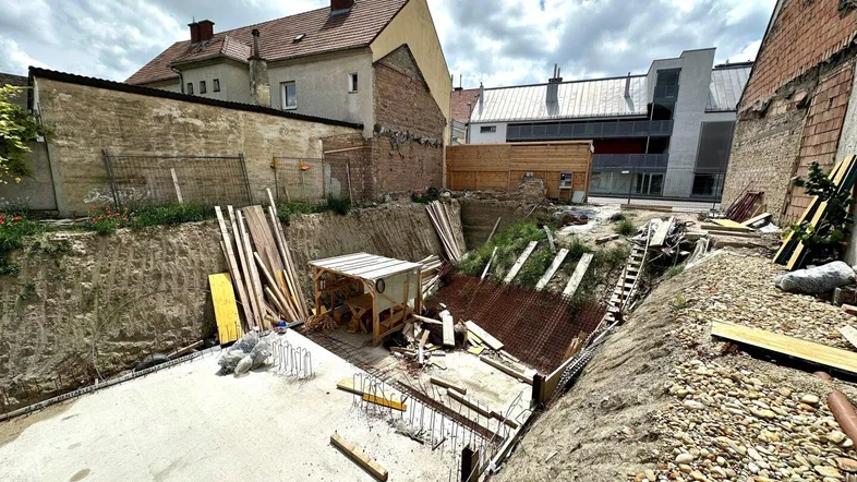 Baustelle mit ausgehobener Baugrube und Fundamentarbeiten für ein neues Gebäude.