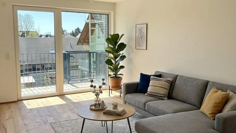 Helles Wohnzimmer mit modernem Sofa, Holzboden und Zugang zu einem sonnigen Balkon.
