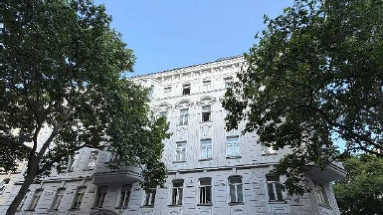 Historisches Gebäude mit aufwendiger Fassadengestaltung und hohen Fenstern unter blauem Himmel.