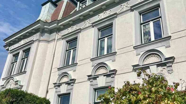 Elegante Fassade eines historischen Gebäudes mit verzierten Fenstern und Mansarddach.