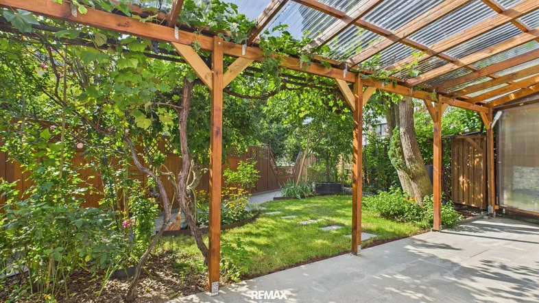 Überdachte Terrasse mit Pergola und üppigem Grün, ideal für entspannte Stunden im Freien.