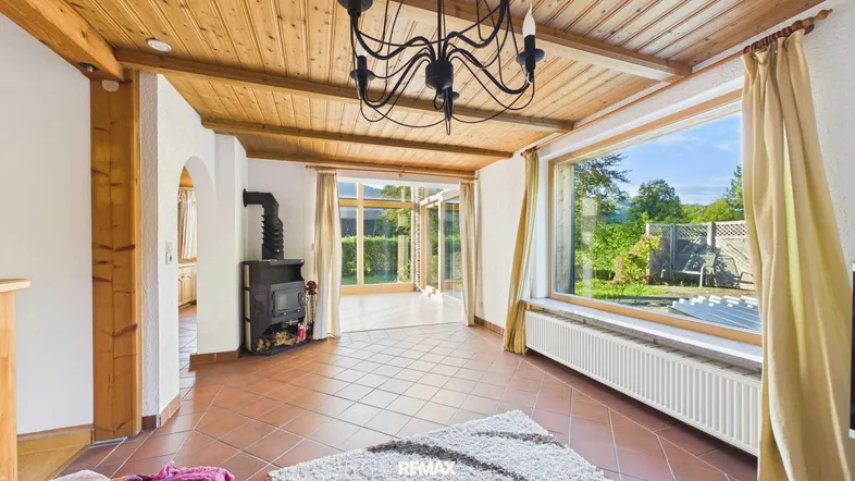 Gemütliches Wohnzimmer mit Holzdecke, Kaminofen und Zugang zum Wintergarten.