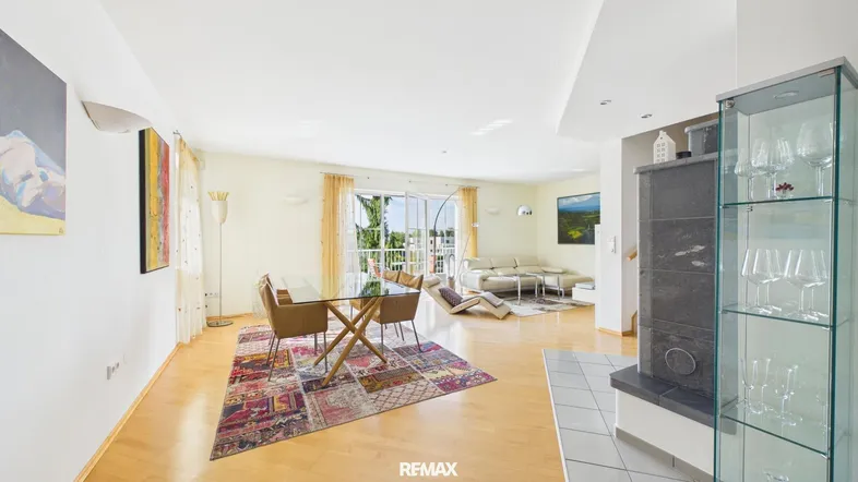 Helles Wohn- und Esszimmer mit Holzboden, Kamin und Zugang zum Balkon.