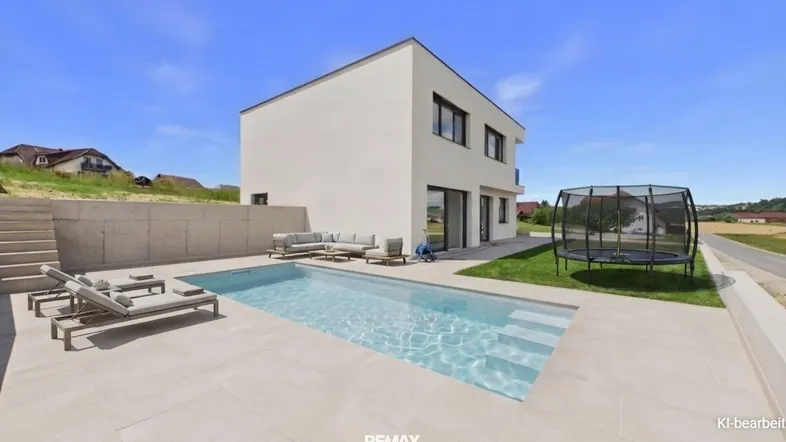 Modernes Einfamilienhaus mit privatem Pool, Liegebereich und Trampolin im sonnigen Garten.