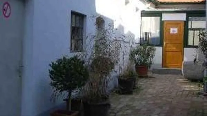 Ein gepflasterter Innenhof zwischen älteren Gebäuden mit Topfpflanzen und einem Terrakottadach.
