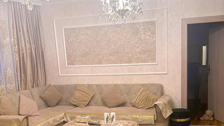 Elegantes Wohnzimmer mit großem Ecksofa, Kronleuchtern und hellem Laminatboden.