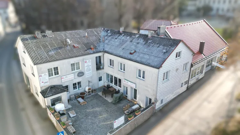 Luftaufnahme eines Gebäudekomplexes mit Innenhof und angrenzenden Straßen in einer ländlichen Umgebung.