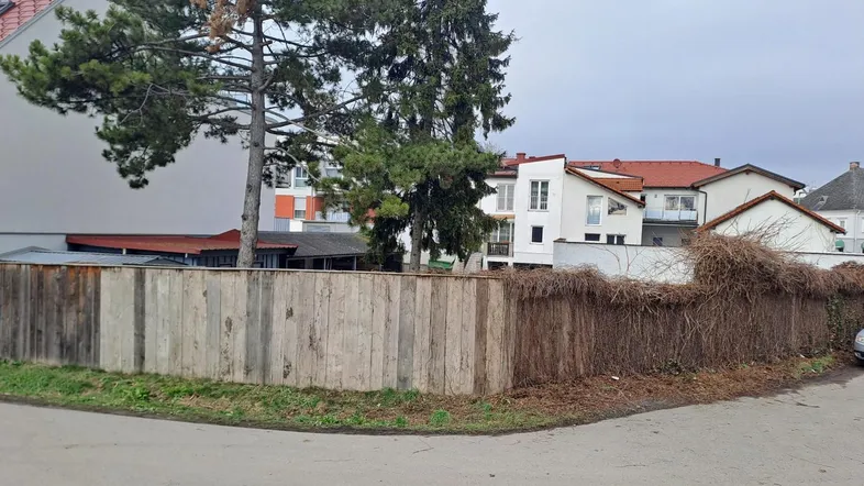 Blick auf einen Holzzaun und die umliegenden Wohngebäude an einer Straßenecke.