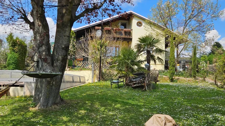 Großzügiger Gartenbereich mit blühender Wiese und einem charmanten Haus im Hintergrund unter blauem Himmel.