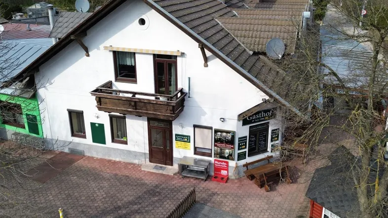 Luftaufnahme des Gasthofs mit traditioneller Architektur, Satteldach und einem kleinen Balkon im ersten Stock.