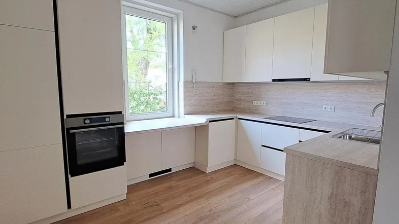 Moderne Einbauküche in Weiß mit Holzoptik-Arbeitsplatte und integriertem Backofen, hell und funktional.