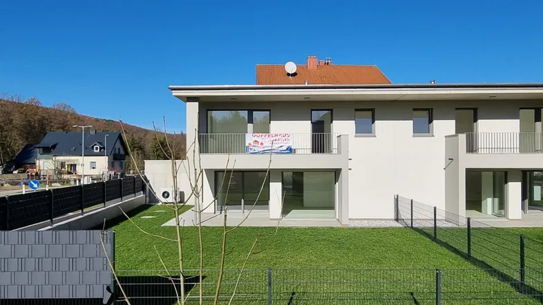 Modernes Doppelhaus mit Garten und Balkonen in sonniger Lage, umgeben von Natur.
