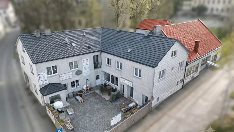 Luftaufnahme eines Gebäudekomplexes mit gepflastertem Innenhof und angrenzenden Straßen.