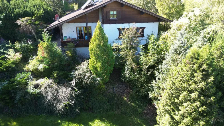 Charmantes Haus mit Satteldach, umgeben von üppigem Grün und Bäumen in ländlicher Umgebung.