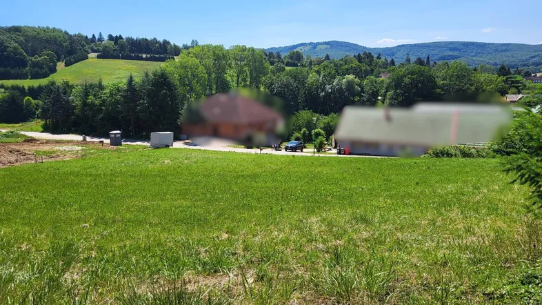 Weitläufiges grünes Grundstück mit Blick auf die umliegende Landschaft und Berge unter blauem Himmel.