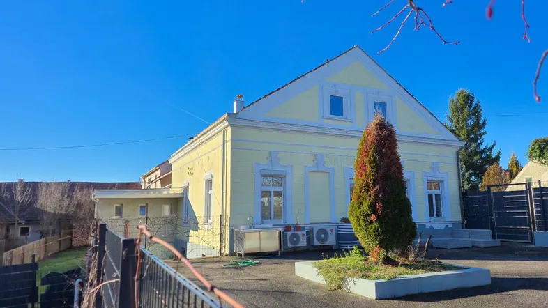 Gelbe Fassade eines traditionellen Hauses mit Klimaanlagen im Außenbereich unter blauem Himmel.